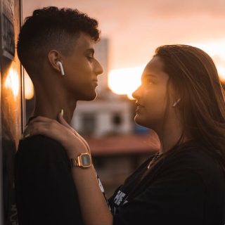 A young couple sharing a tender moment outdoors during sunset, symbolizing love and togetherness.